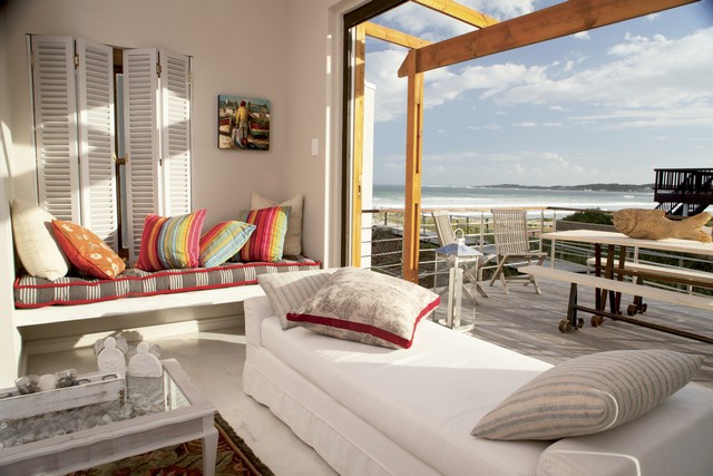Living room and terrace with an ocean view - cozy upholstered day beds by an open picture window in front of a terrace